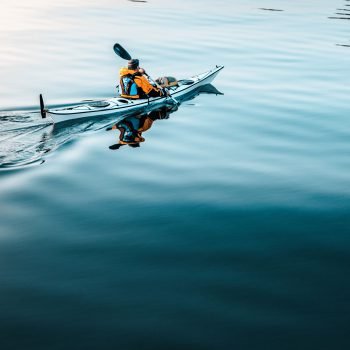 Imagen de hombre remando en kayak en una mar calmado